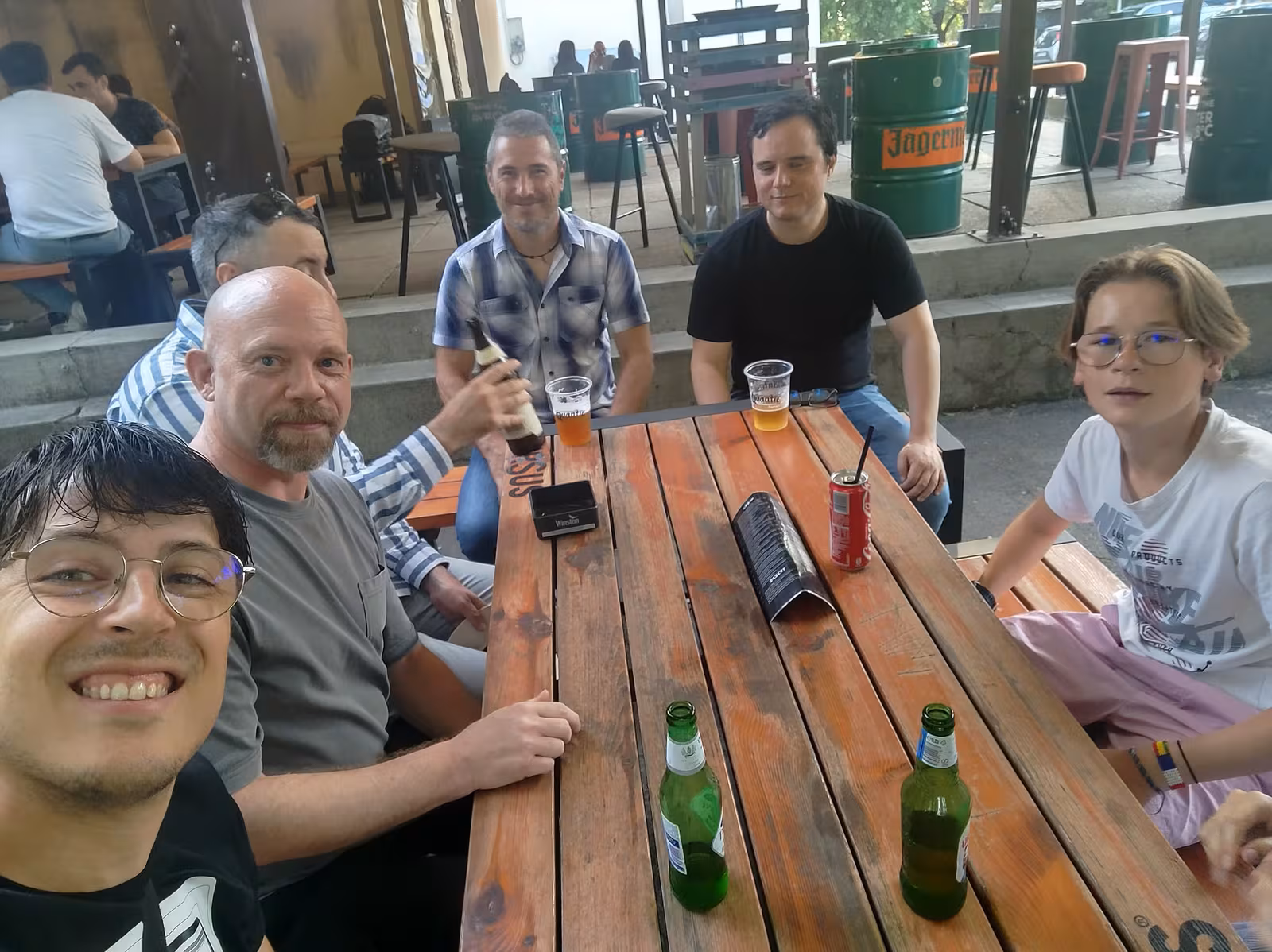 Members sharing a wooden table at a terrace bar