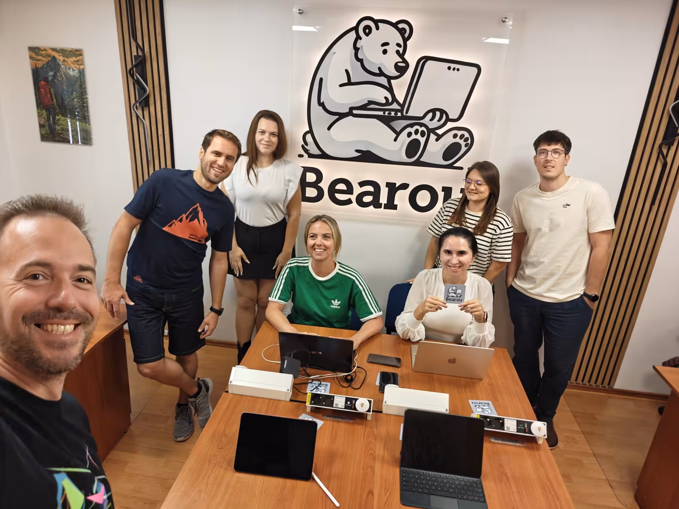 The group around a desk of laptops under the Bearou Coworking bear logo