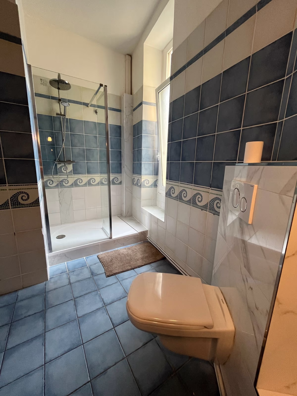 The walk-in shower in the blue tiled bathroom