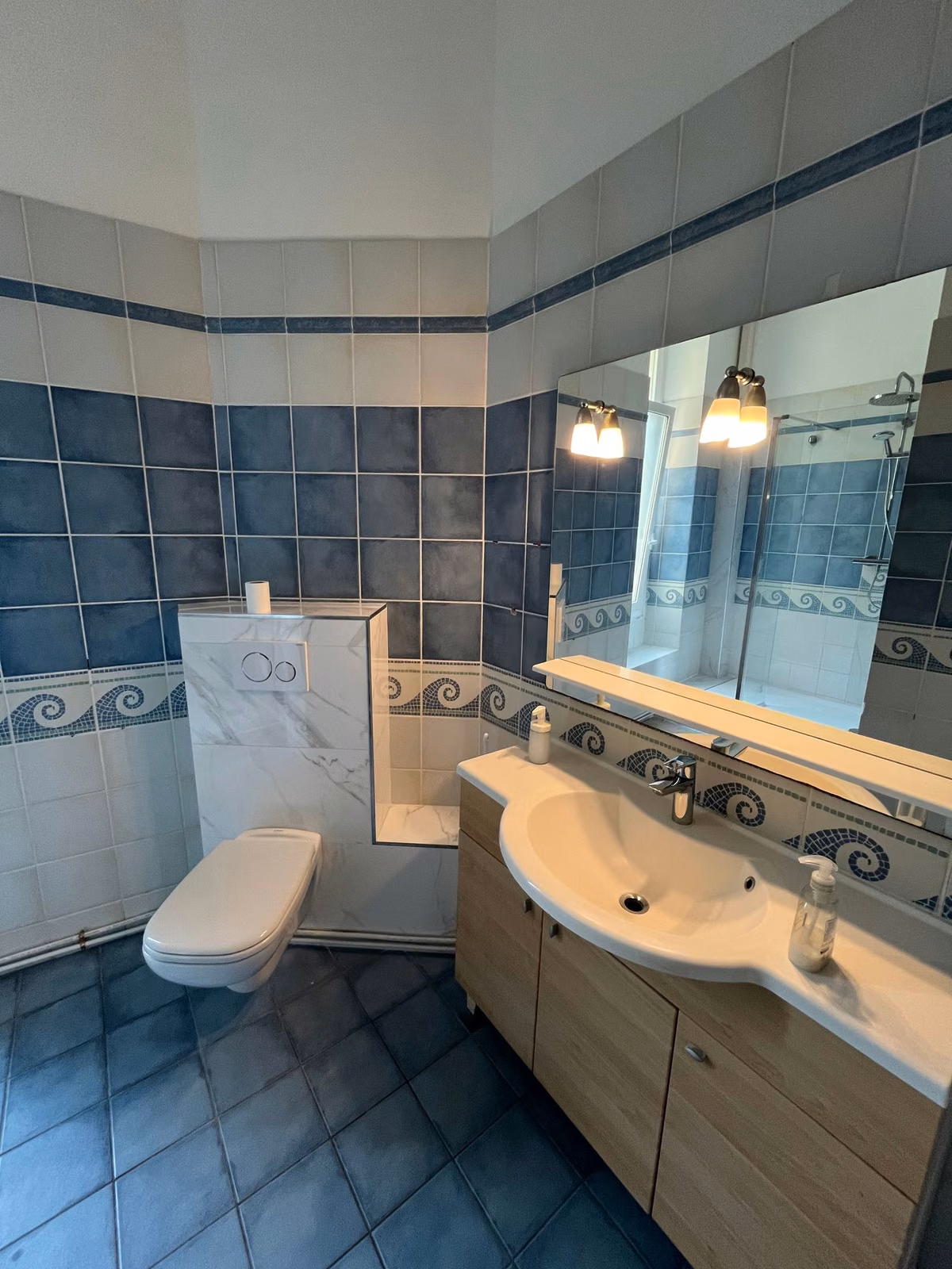 One of the two shared bathrooms, with a washbasin and blue tiled walls