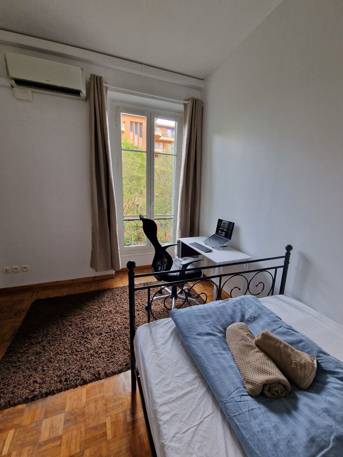 A double room with a wrought-iron bed and towels folded on the end