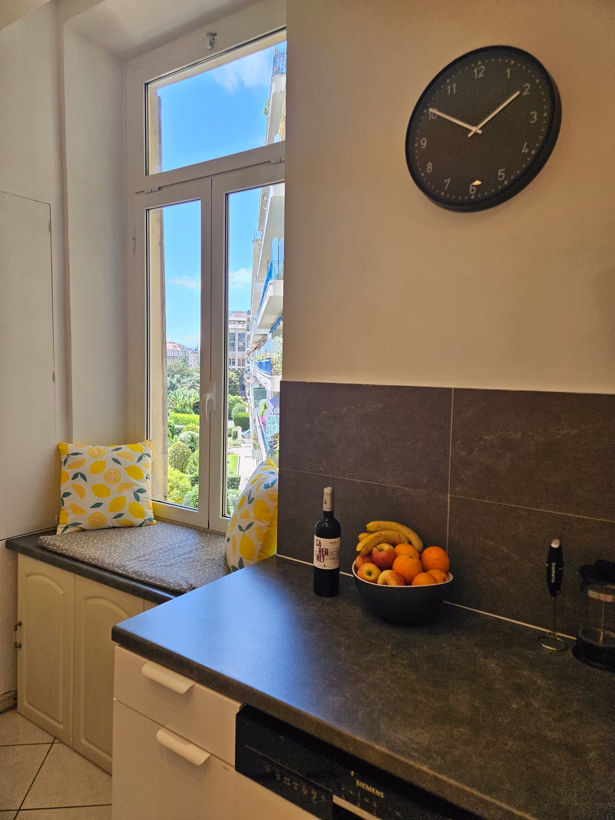The kitchen counter beside a cushioned window seat and a bowl of oranges