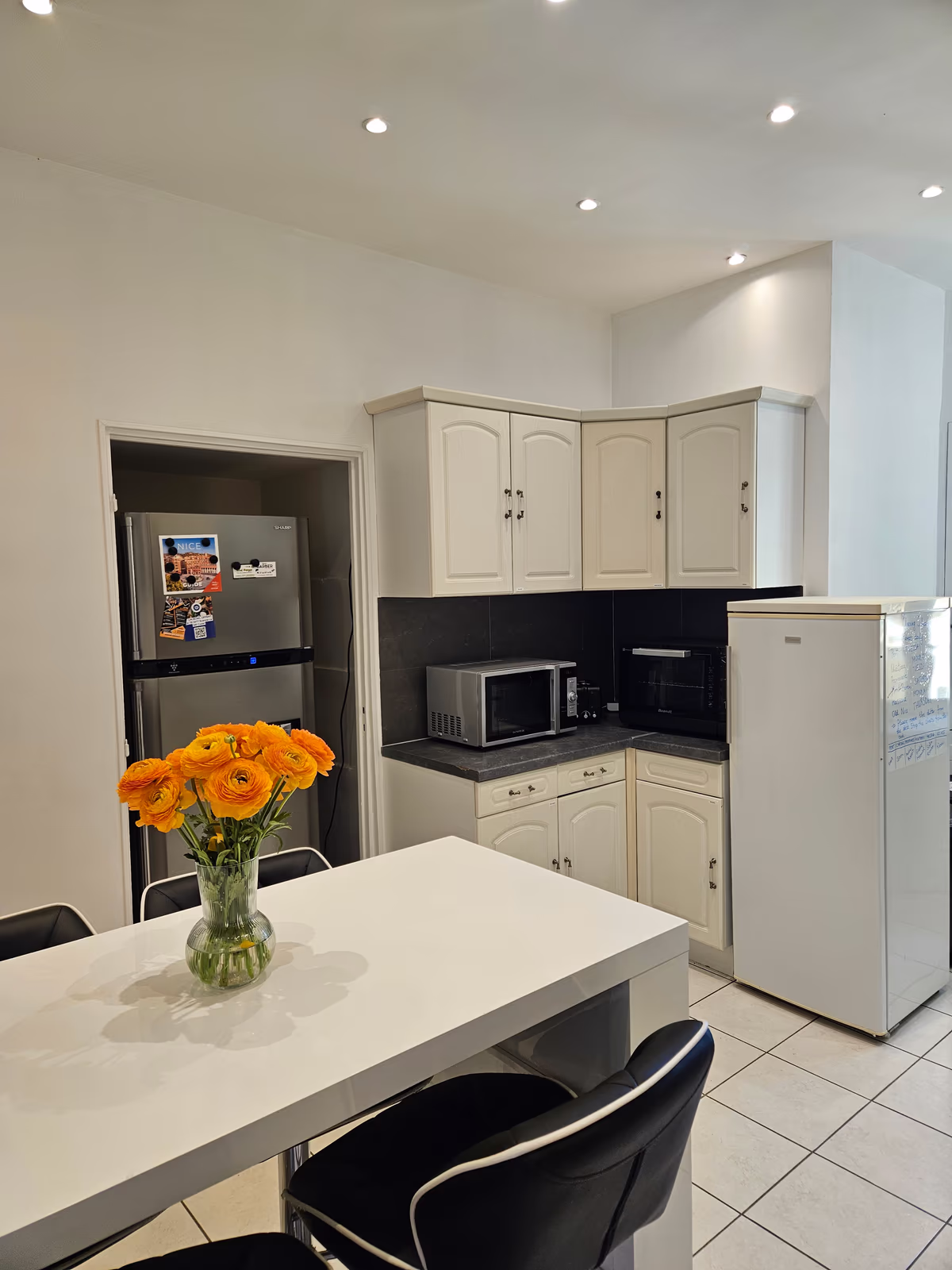 The breakfast bar with a vase of orange flowers, and the two fridges behind it