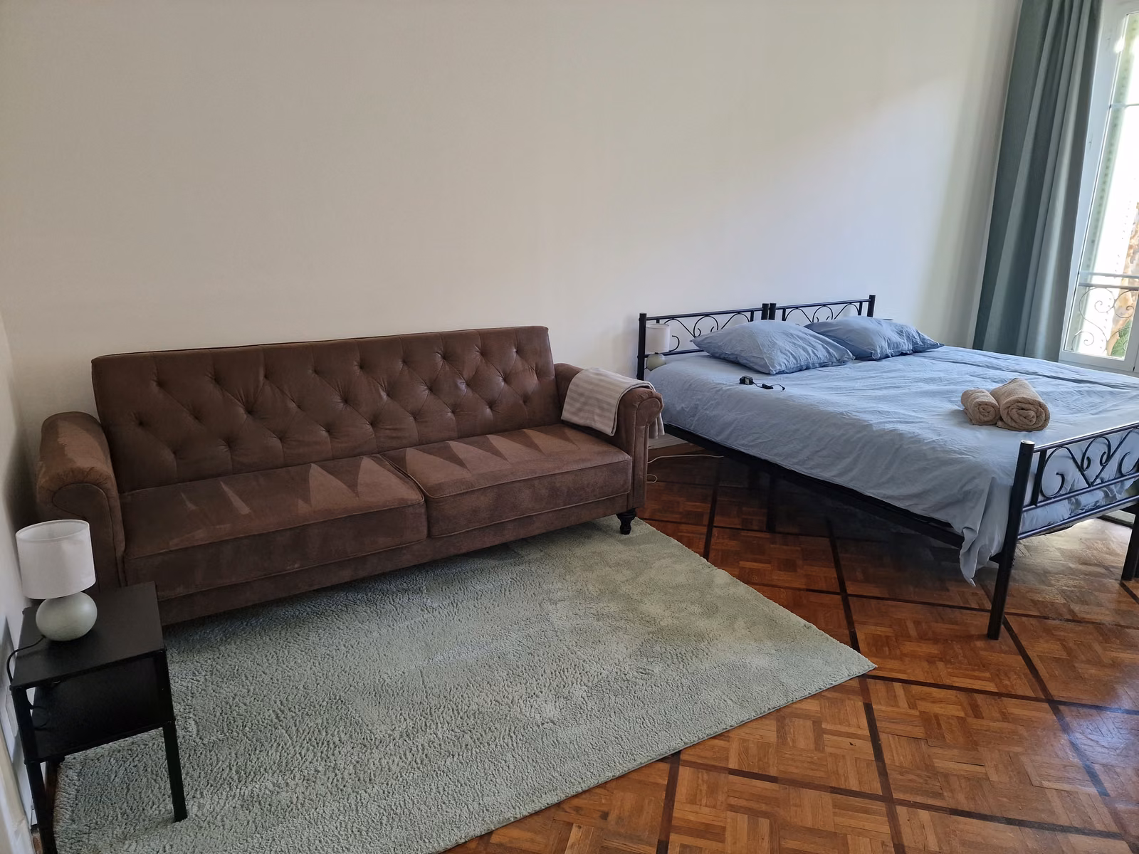 The twin XL room's sofa next to the bed, with folded towels