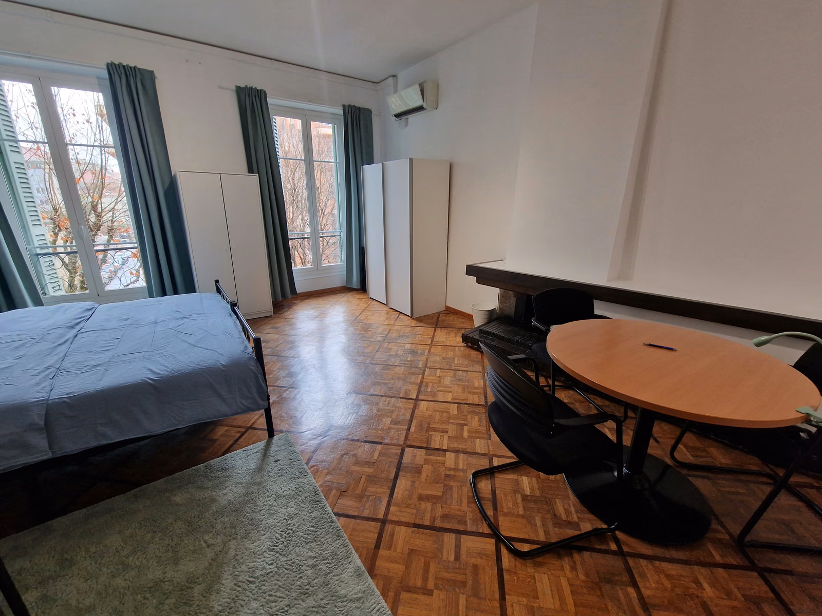 The twin XL room's round table and wardrobes beside the windows