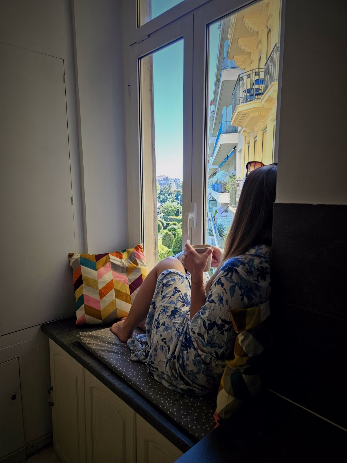 A coliver reading on the window seat of the apartment in Nice